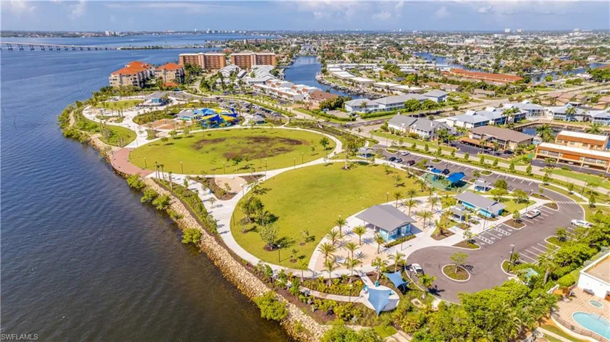 Jaycee Park-Expansive waterfront park area featuring pedestrian pathways, extensive green spaces, a water park with slides, dedicated parking areas, and mature palm trees