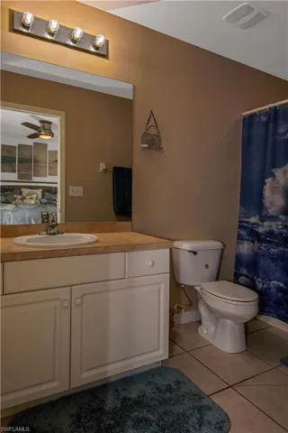 Full bathroom featuring light tile patterned floors, vanity, ceiling fan, and curtained shower