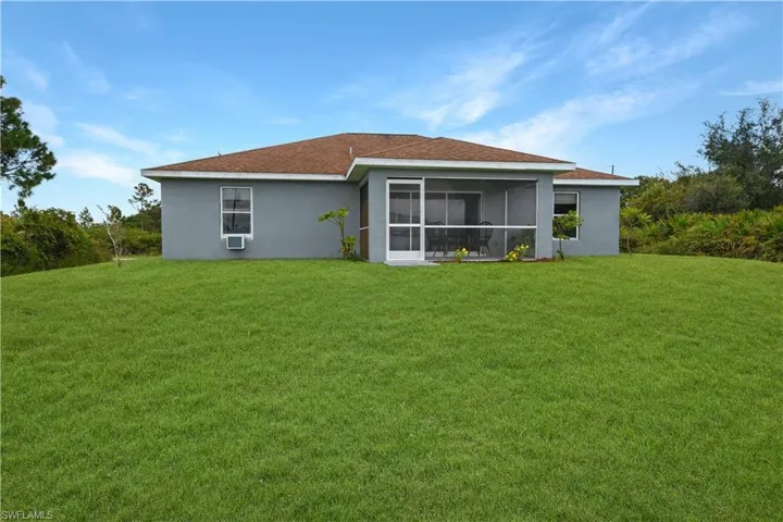 Back of house featuring a lawn, stucco siding, a sunroom, and roof with shingles