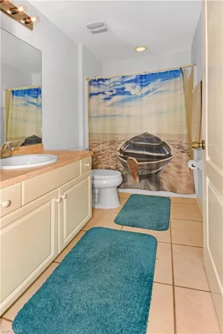Bathroom with light tile patterned flooring, vanity, curtained shower, and recessed lighting