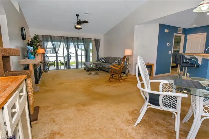 Living area with a ceiling fan, light colored carpet, and lofted ceiling