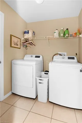 Laundry area with light tile patterned flooring and washer and clothes dryer