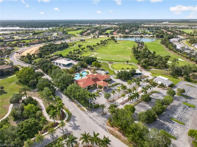 Aerial perspective showcasing a vibrant community with a central clubhouse featuring a barrel tile roof and an adjacent swimming pool