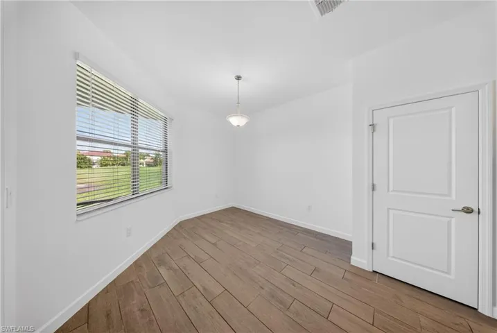 Bright room featuring wood-finish flooring, a large window with horizontal blinds, a ceiling-mounted light fixture, and a two-panel interior door