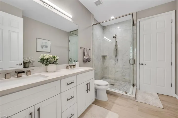 Bathroom with double vanity and a marble finish shower