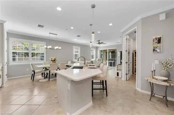 Kitchen featuring ornamental molding, an island with sink, healthy amount of natural light, a breakfast bar, and ceiling fan