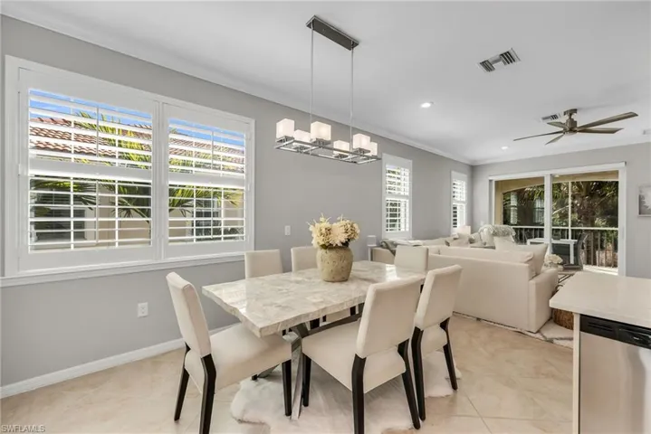 Dining area featuring ceiling fan, ornamental molding, light tile patterned floors, and suspended lighting