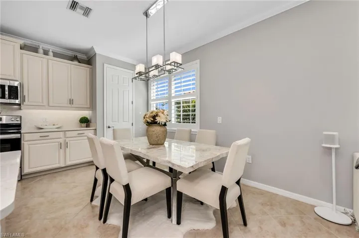 Dining area featuring ornamental molding, a chandelier, and light tile patterned floors