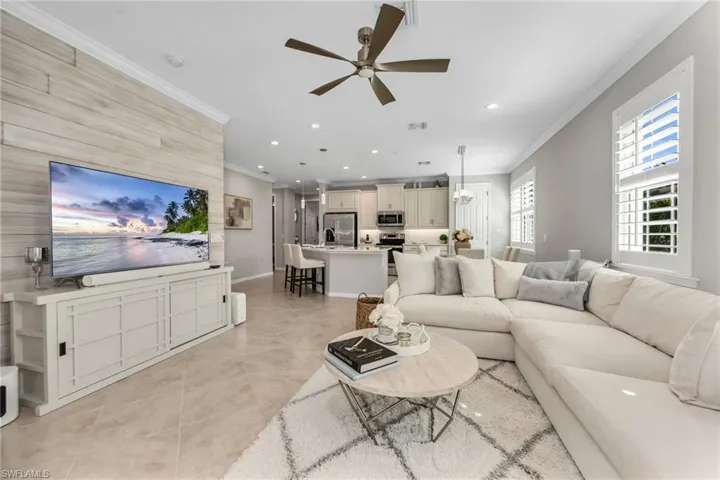 Living room with recessed lighting, a ceiling fan, crown molding, light tile patterned floors, and an accent wall