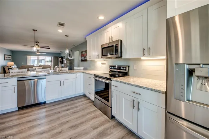 Spacious Kitchen featuring Breakfast Bar, Quartz Countertops, Custom Lighting, Subway Backsplash, SS Appliances & New Flooring Throughout.