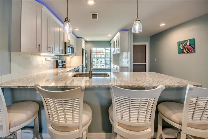 Kitchen featuring appliances with stainless steel finishes, a kitchen breakfast bar, and pendant lighting