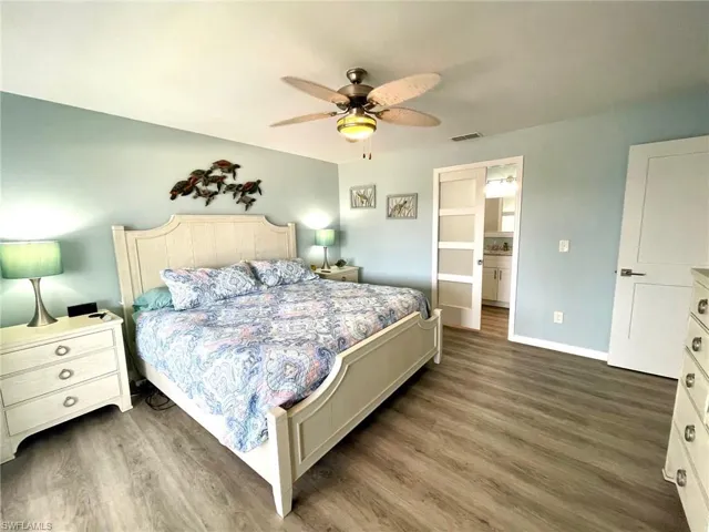 Bedroom with ceiling fan, ensuite bath, and dark hardwood / wood-style flooring