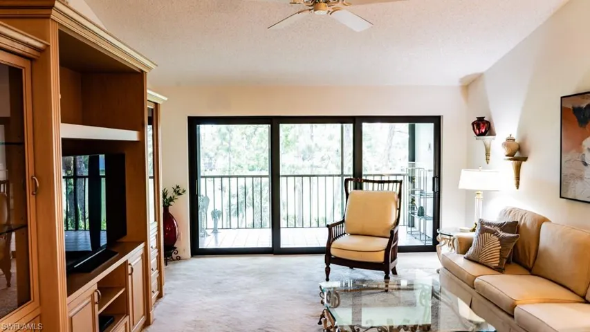 Living area featuring light carpet, a textured ceiling, and a ceiling fan