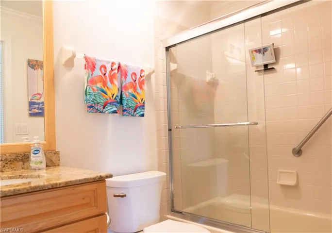 Full bath with crown molding, vanity, and bath / shower combo with glass door