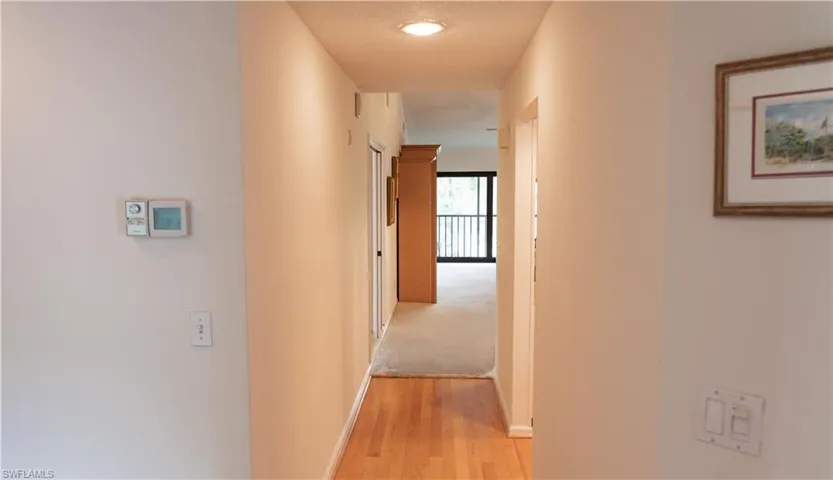 Hallway with light wood-type flooring and a textured ceiling
