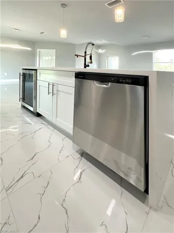 Kitchen featuring pendant lighting, beverage cooler, white cabinetry, and dishwasher