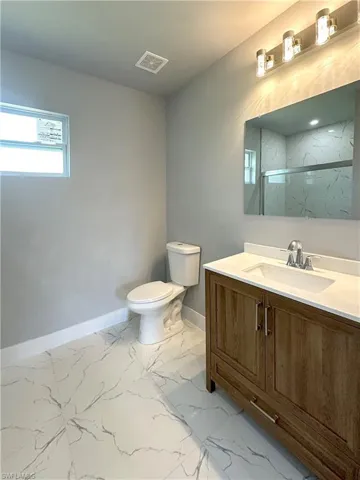 Bathroom featuring vanity, toilet, and a shower with shower door