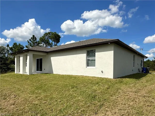 Back of house featuring a yard and central AC