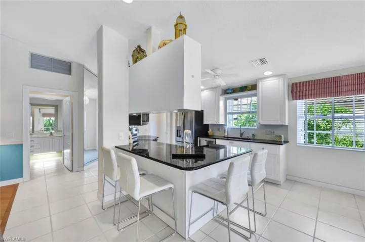 Kitchen featuring white cabinetry, light tile patterned floors, a breakfast bar area, and ceiling fan