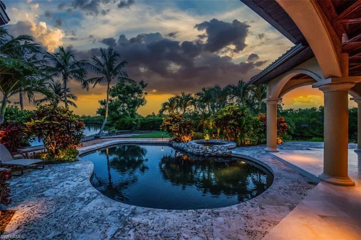 Pool at dusk with a patio area and a pool with connected hot tub