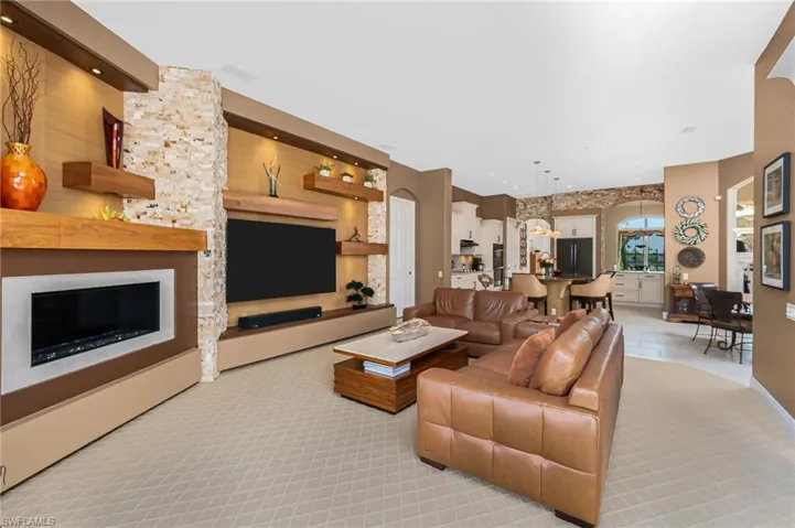 Living room with light carpet, a large fireplace, recessed lighting, and arched walkways