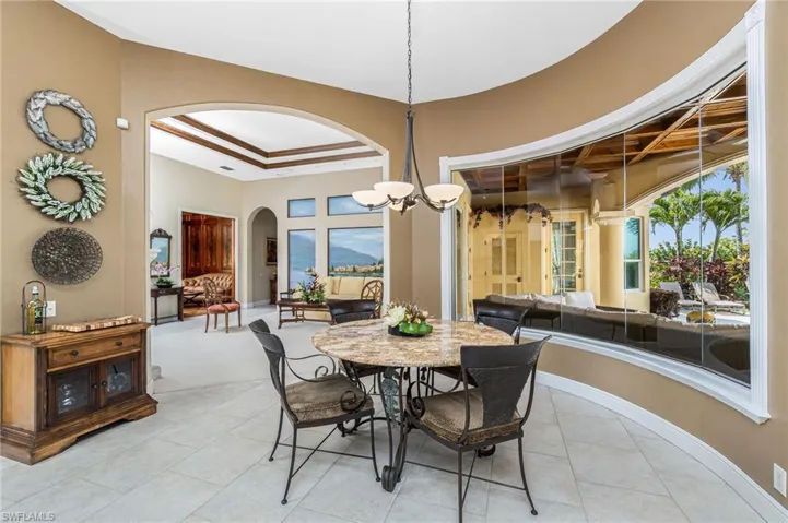 Dining area with a tray ceiling, a chandelier, arched walkways, and light tile patterned floors