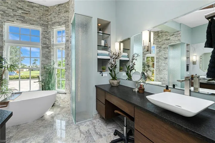 Full bathroom with vanity, a stall shower, a freestanding tub, and a high ceiling