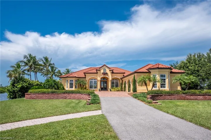 Mediterranean / spanish house with stucco siding, driveway, a front yard, and a tiled roof