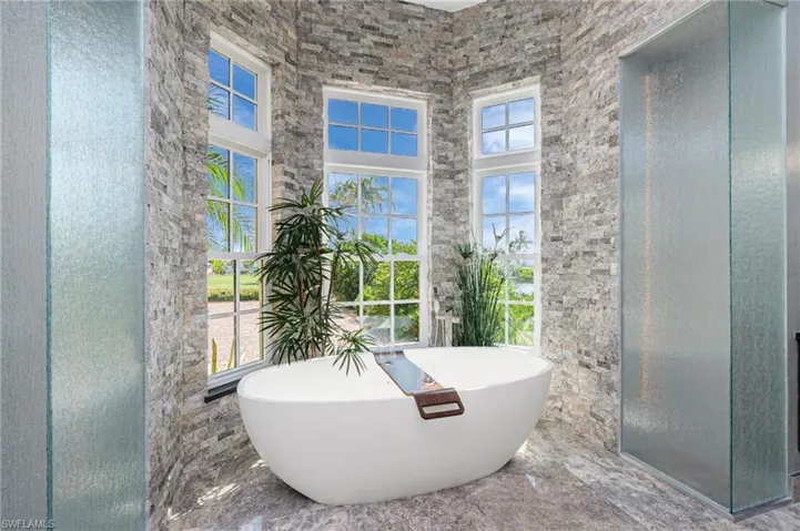 Full bath with a freestanding tub, a stall shower, and a high ceiling