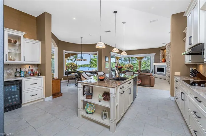 Kitchen featuring decorative backsplash, light stone counters, beverage cooler, decorative light fixtures, and glass fronted cabinets