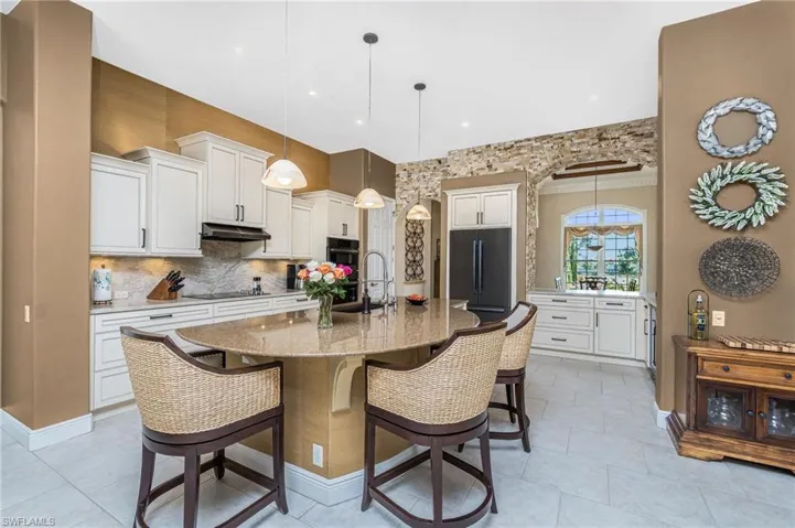 Kitchen featuring a kitchen breakfast bar, white cabinets, black appliances, tasteful backsplash, and ornamental molding