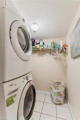 Laundry room featuring stacked washer / drying machine and a textured ceiling