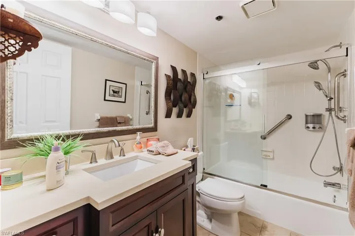 Bathroom with vanity, shower / bath combination with glass door, and light tile patterned flooring