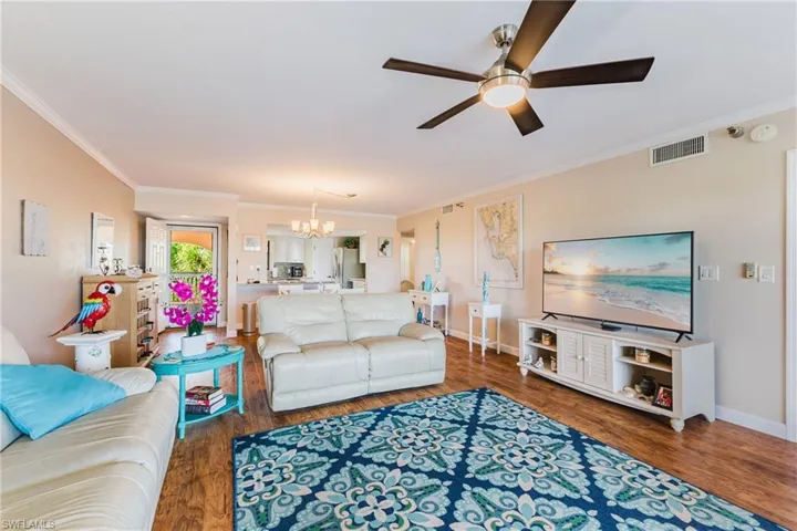 Living area featuring hanging lights, dark wood finished floors, crown molding, and ceiling fan