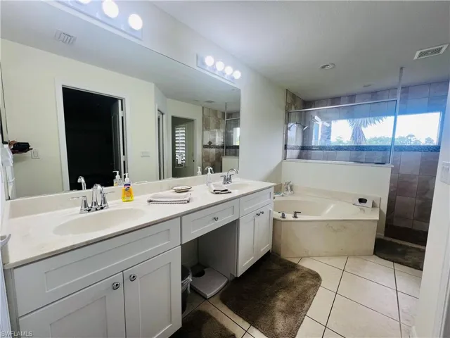 Master Bathroom with tile patterned floors, shower with separate bathtub, and double sink vanity