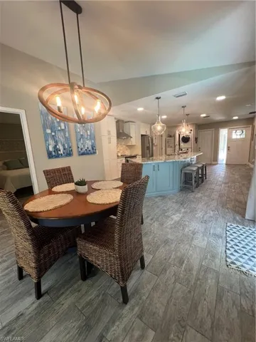 Dining area with light wood-type flooring, washer / clothes dryer, and suspended lighting