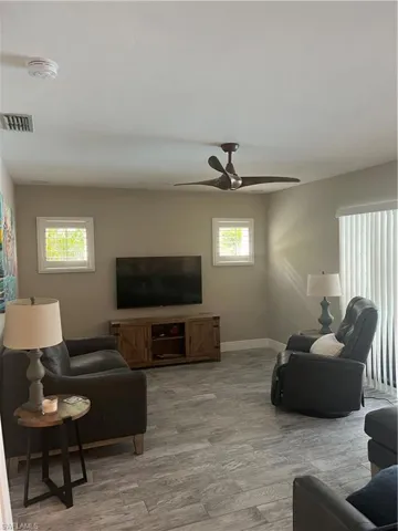 Living room with light wood-type flooring and a ceiling fan