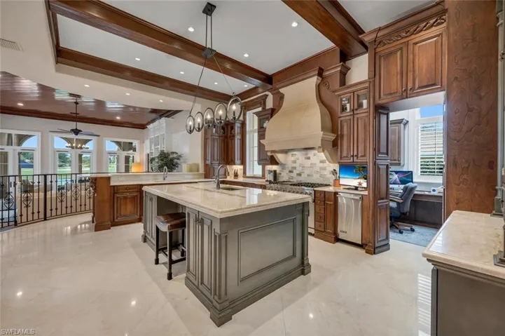 Kitchen featuring decorative light fixtures, a breakfast bar area, brown cabinets, light stone counters, and appliances with stainless steel finishes