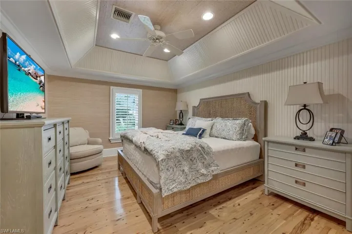 Bedroom featuring a raised ceiling, ceiling fan, light wood finished floors, ornamental molding, and recessed lighting