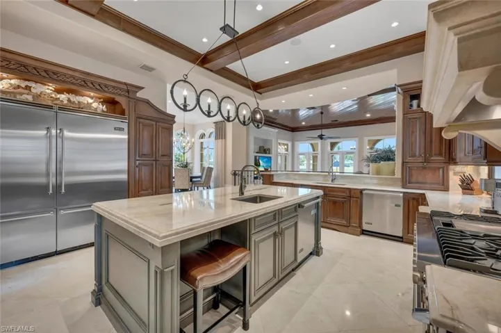 Kitchen with appliances with stainless steel finishes, a center island with sink, a peninsula, premium range hood, and a breakfast bar