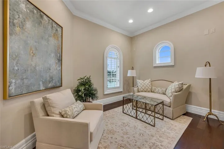 Sitting room with dark wood-style flooring, crown molding, and recessed lighting