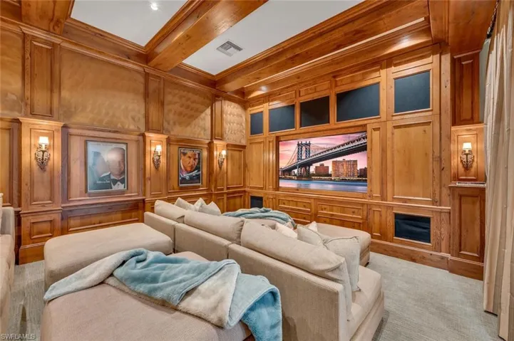 Cinema with wood walls, a decorative wall, beam ceiling, and ornamental molding