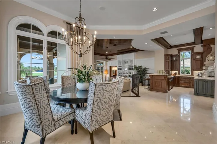 Dining area featuring crown molding, a chandelier, ceiling fan, and a raised ceiling