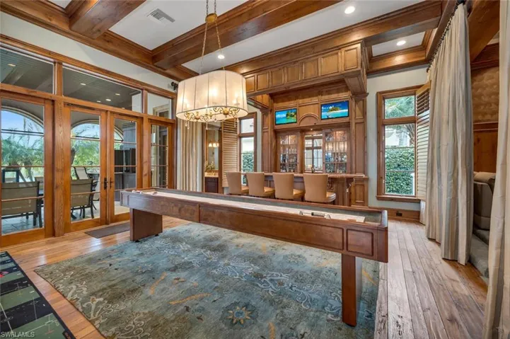 Rec room with french doors, light wood-style floors, a chandelier, beamed ceiling, and ornamental molding