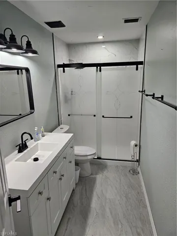 Bathroom with vanity, toilet, and an enclosed shower
