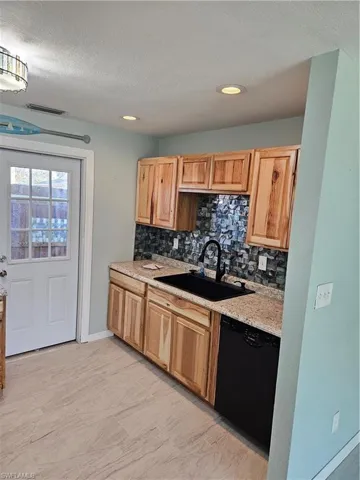 Kitchen featuring dishwasher, decorative backsplash, a textured ceiling, and sink