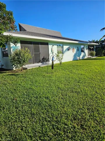 Rear view of house featuring a sunroom and a lawn