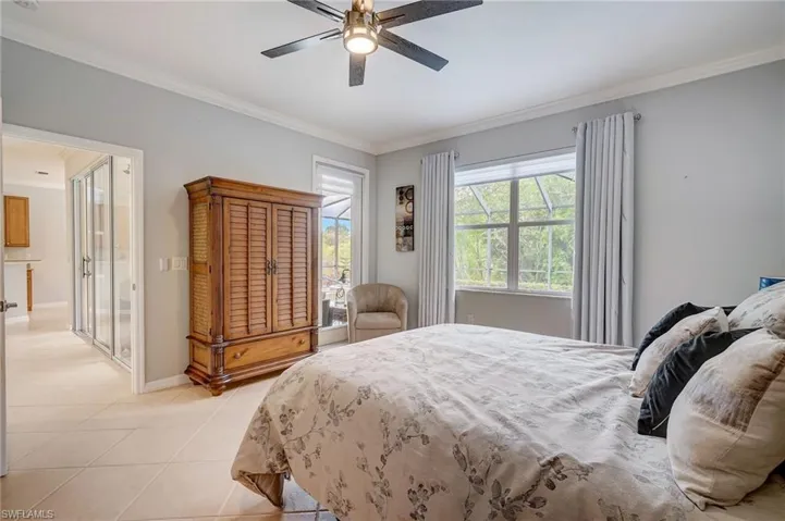 Bedroom with ceiling fan, ornamental molding, and light tile patterned floors