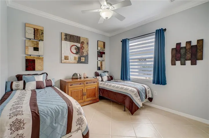 Tiled bedroom with ceiling fan and crown molding