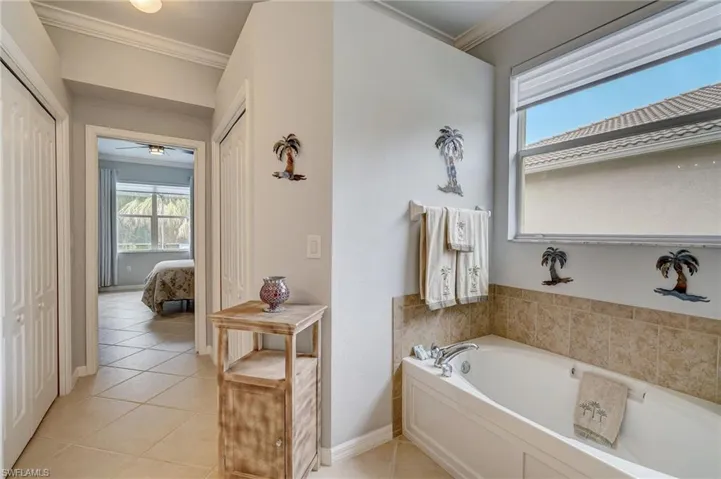 Bathroom featuring tile patterned flooring, ornamental molding, and a bath